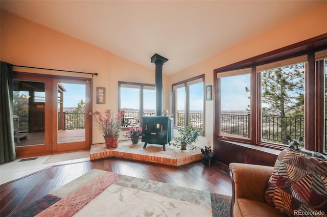 sunroom featuring lofted ceiling, a wood stove, and visible vents