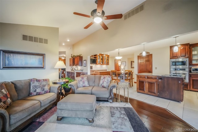 living area with ceiling fan, light wood finished floors, lofted ceiling, and visible vents