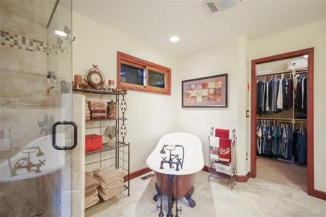 bathroom featuring a spacious closet, a freestanding tub, a shower stall, and visible vents