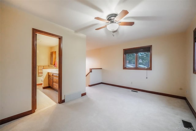 spare room featuring light carpet, visible vents, and baseboards