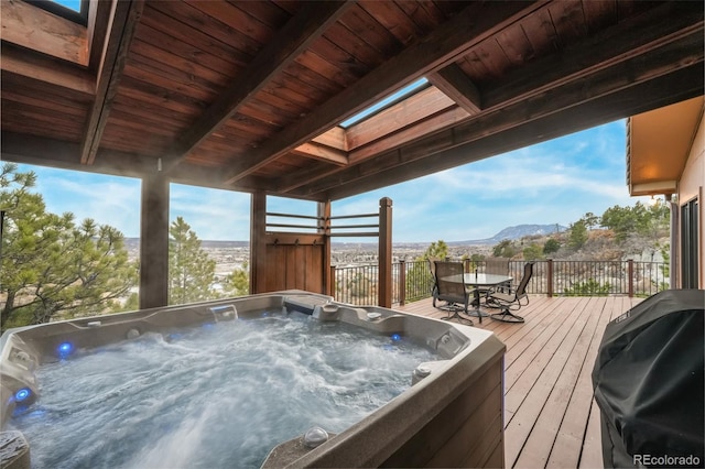 wooden terrace with a mountain view, a hot tub, and area for grilling