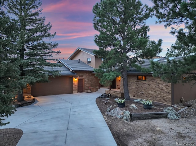 view of front of house featuring a tile roof, driveway, and an attached garage