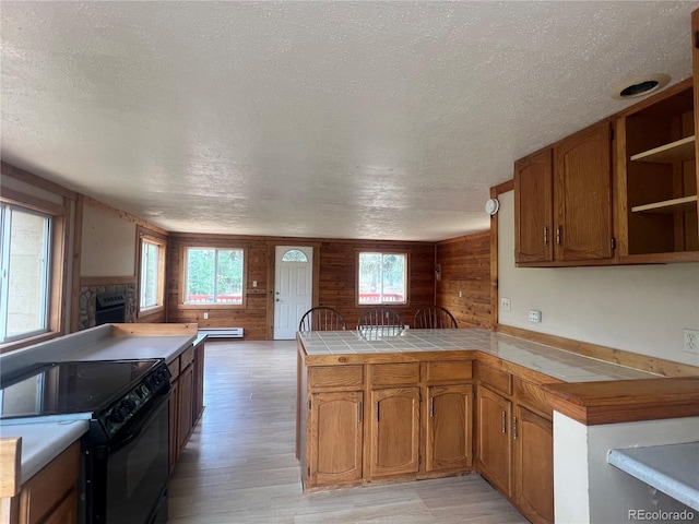 95 Appleby St, Bailey, CO 80421 - kitchen featuring black electric range oven, wooden walls, a peninsula, a textured ceiling, and plenty of natural light
