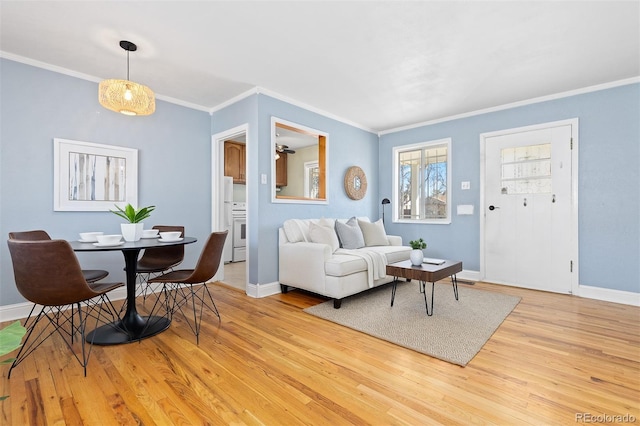 living area featuring baseboards, light wood-style flooring, and crown molding