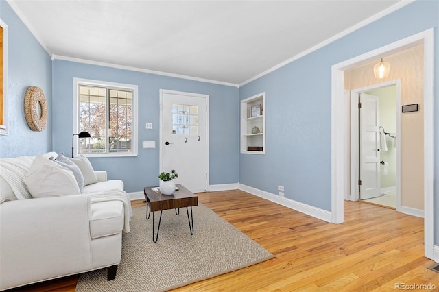 living room with light wood finished floors, baseboards, built in shelves, and ornamental molding