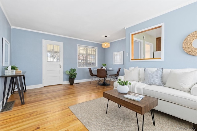 living room with light wood finished floors, visible vents, baseboards, and crown molding