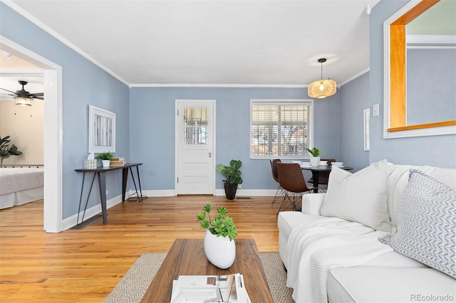 living room featuring light wood-style flooring, ornamental molding, ceiling fan, and baseboards