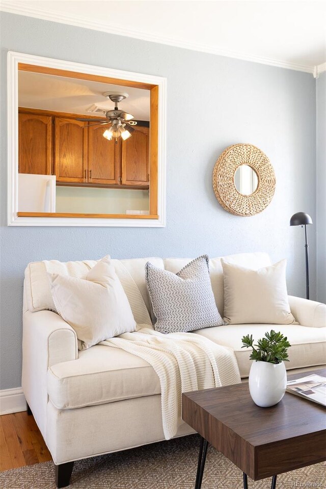 living room featuring ceiling fan, ornamental molding, wood finished floors, and baseboards