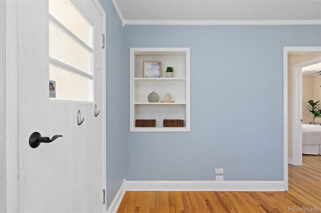 interior space featuring crown molding, baseboards, and wood finished floors