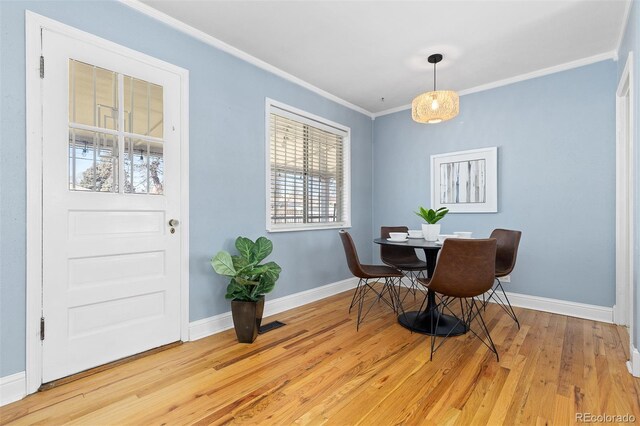 dining area with baseboards, light wood-type flooring, and crown molding