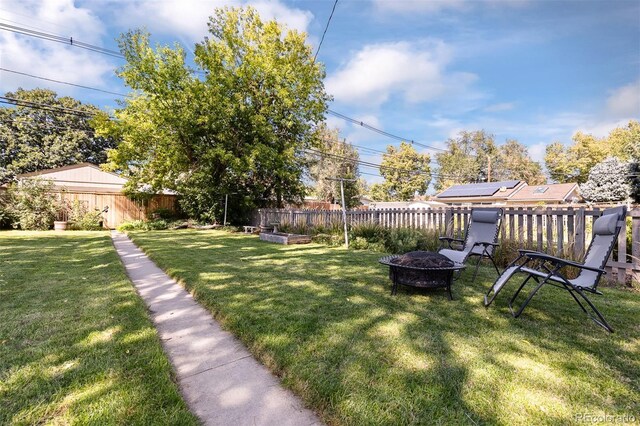 view of yard featuring a garden, a fenced backyard, and a fire pit