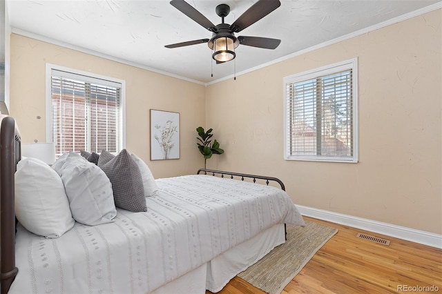 bedroom featuring visible vents, ornamental molding, ceiling fan, wood finished floors, and baseboards