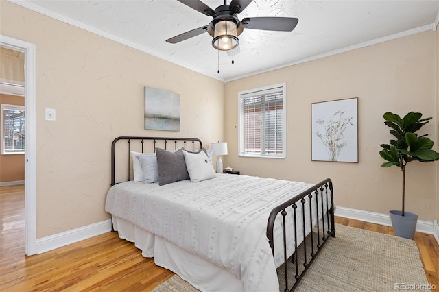 bedroom with baseboards, ornamental molding, ceiling fan, and wood finished floors