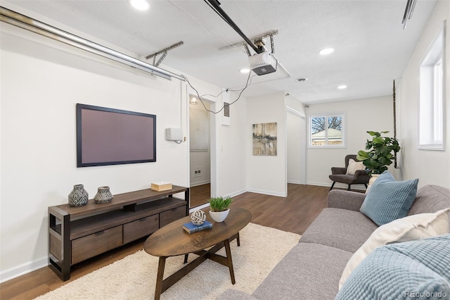 living area featuring recessed lighting, a textured ceiling, wood finished floors, a garage, and baseboards