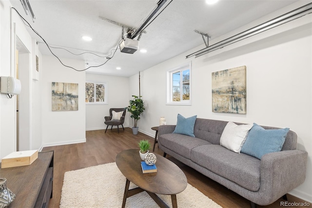 living room featuring a garage, baseboards, and wood finished floors