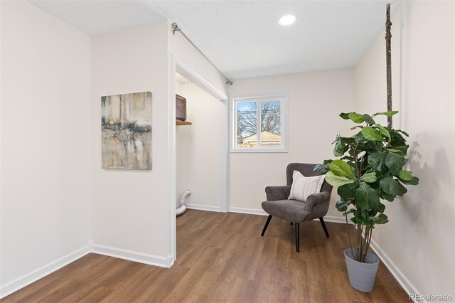 sitting room with baseboards, wood finished floors, and recessed lighting