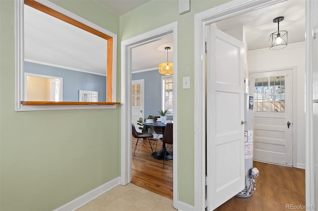 hallway with baseboards, ornamental molding, and wood finished floors