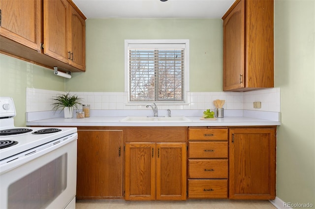 kitchen featuring light countertops, brown cabinetry, a sink, and white range with electric stovetop