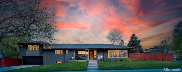 view of front facade featuring a chimney, fence, a garage, driveway, and a front lawn