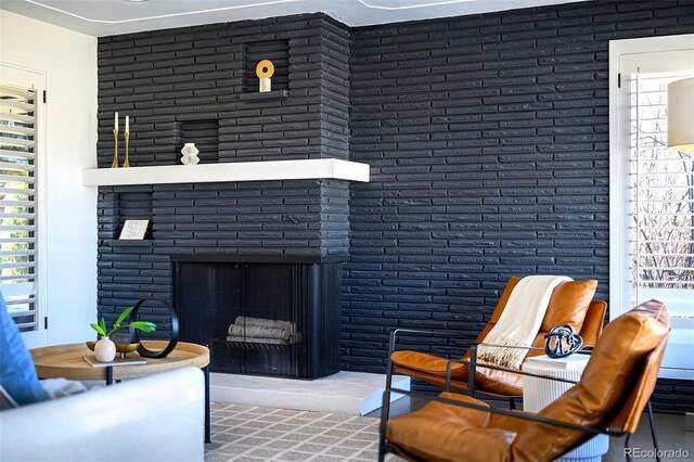 living area featuring brick wall and a fireplace