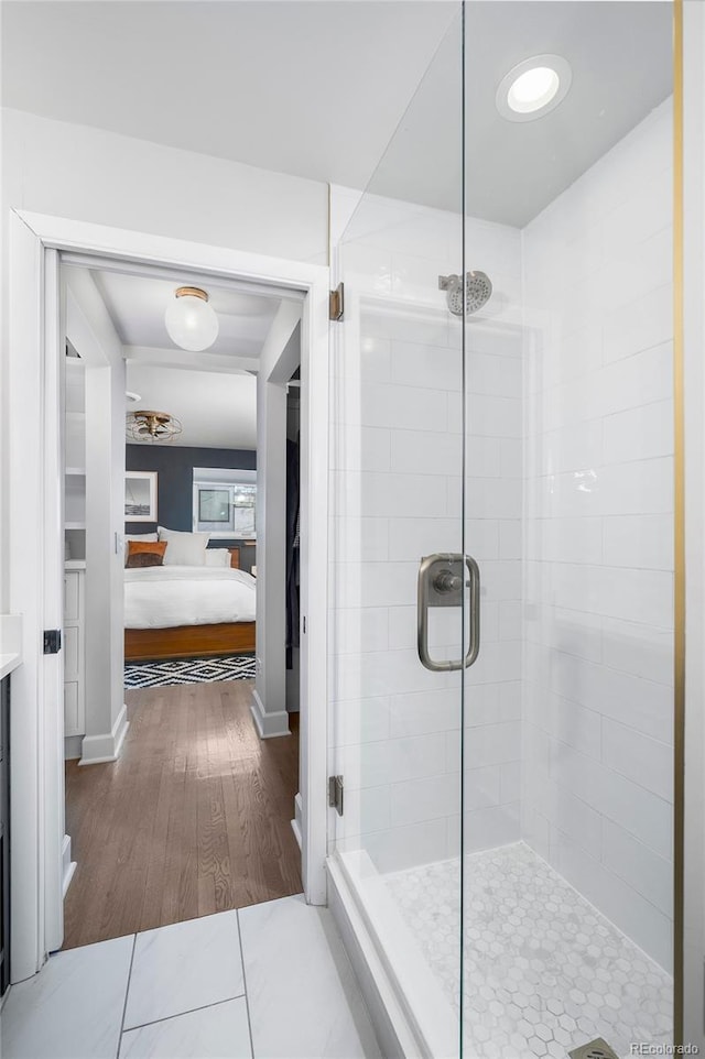 ensuite bathroom featuring wood finished floors, vanity, a shower stall, ensuite bath, and baseboards