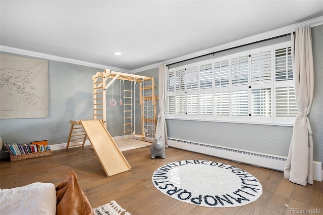 interior space featuring a baseboard radiator, wood finished floors, and crown molding