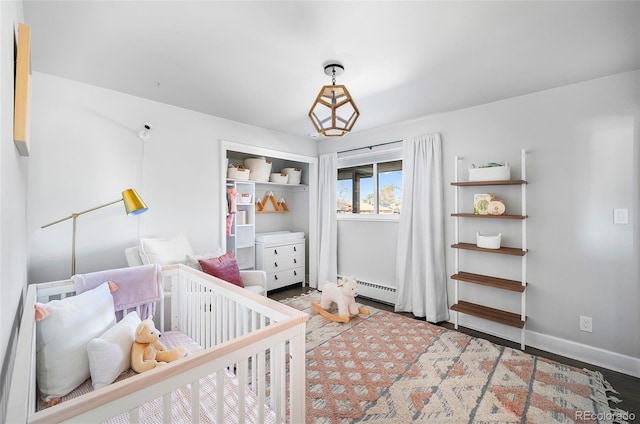 bedroom with a nursery area, wood finished floors, and baseboards