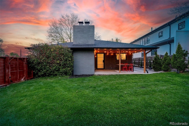 back of house with a patio area, a chimney, fence, and a lawn