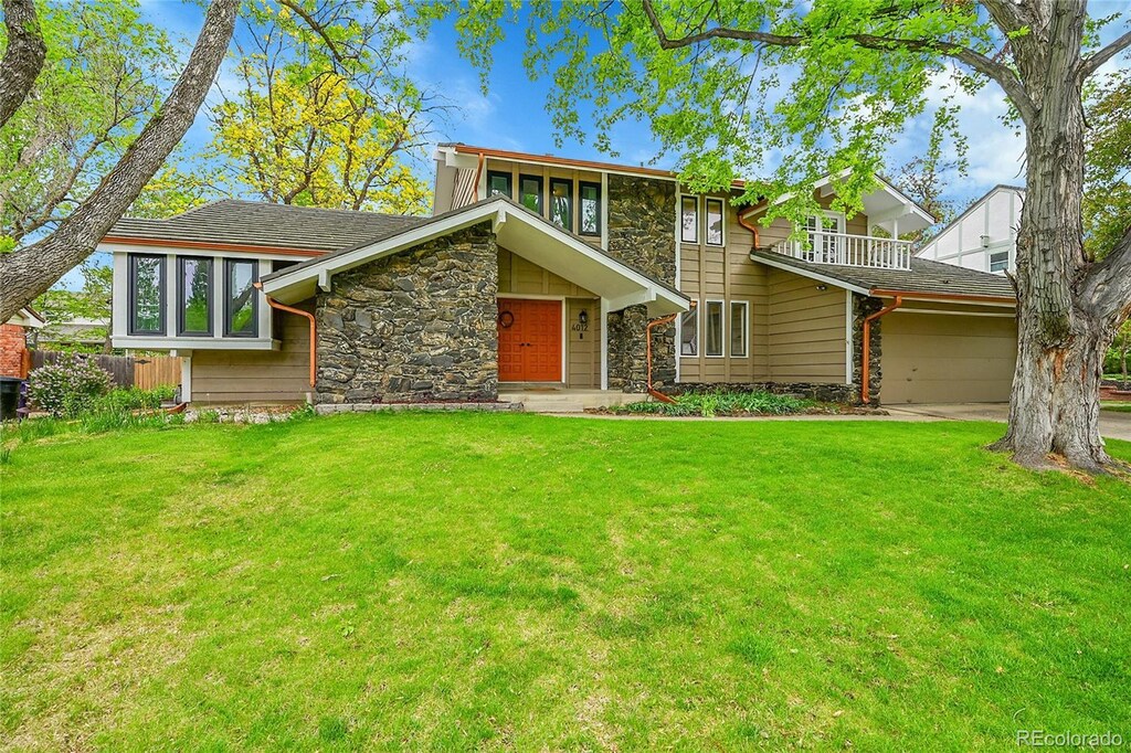 4012 S Newport Way, Denver, CO 80237 - view of front of home featuring stone siding, a garage, and a balcony