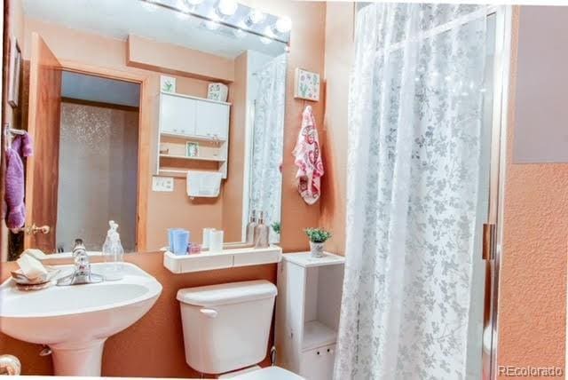 bathroom featuring toilet, a shower with shower curtain, and a sink