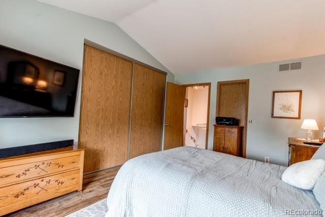 bedroom with vaulted ceiling, light wood-style flooring, a closet, and visible vents