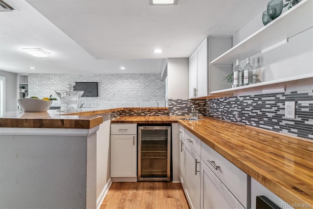 kitchen featuring decorative backsplash, open shelves, light wood finished floors, beverage cooler, and butcher block countertops