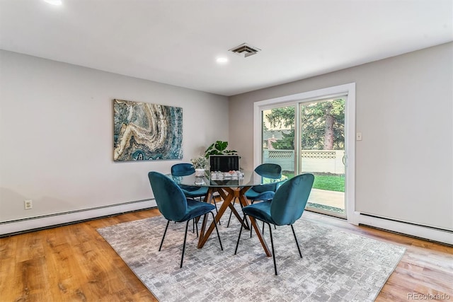 dining space featuring visible vents, a baseboard radiator, wood finished floors, and baseboard heating
