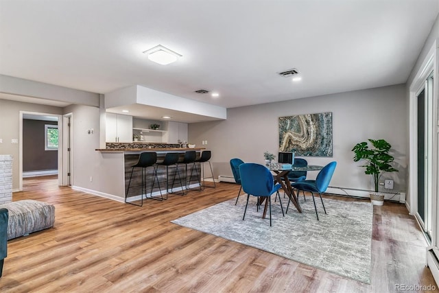 dining room with visible vents, baseboards, baseboard heating, light wood-type flooring, and a baseboard radiator