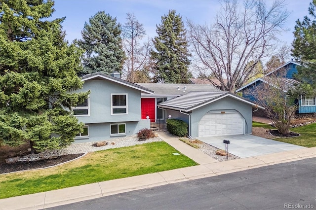 split level home featuring an attached garage, a tile roof, stucco siding, a front yard, and concrete driveway