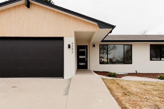 view of front of home with a garage, driveway, a shingled roof, and stucco siding