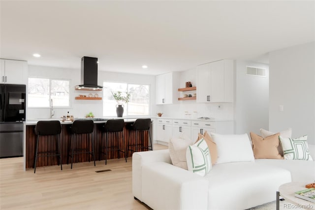 living area featuring recessed lighting, visible vents, and light wood-style floors