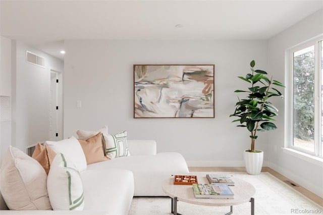 living area with plenty of natural light, visible vents, and baseboards