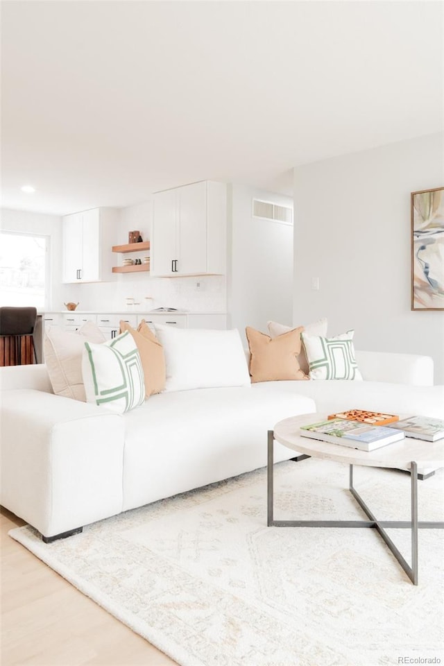 living room featuring light wood-style flooring and visible vents