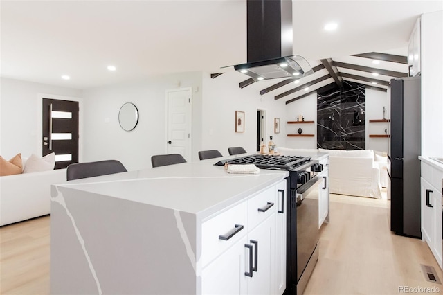 kitchen featuring freestanding refrigerator, light wood-style flooring, island exhaust hood, and black gas stove