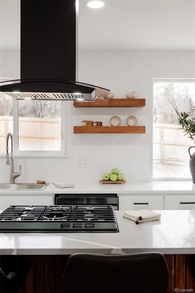 kitchen with plenty of natural light, light countertops, island exhaust hood, and a sink