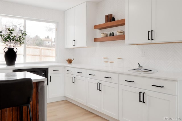 kitchen with light countertops, open shelves, decorative backsplash, and white cabinetry