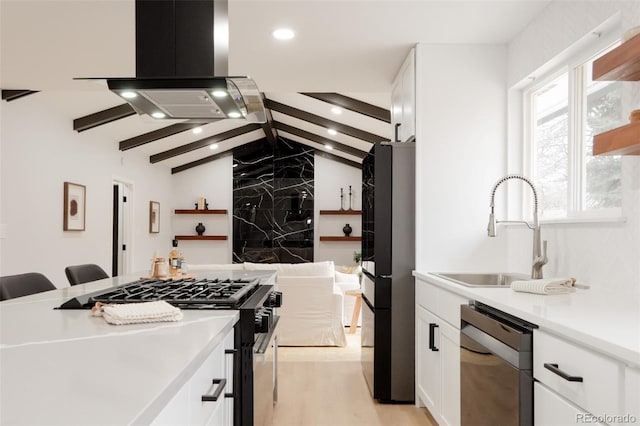 kitchen featuring lofted ceiling with beams, island range hood, stainless steel appliances, a sink, and white cabinetry