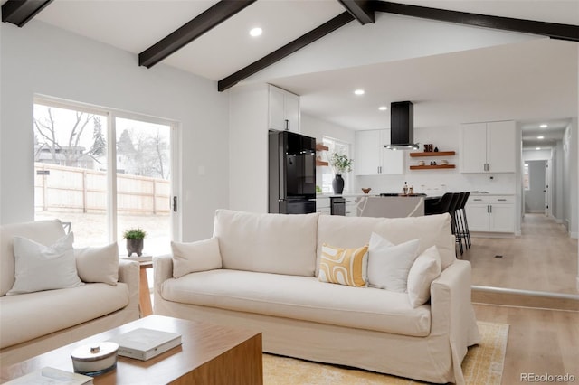 living area featuring light wood-style floors, recessed lighting, and lofted ceiling with beams