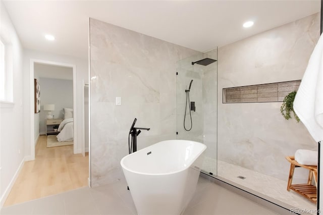 ensuite bathroom featuring ensuite bath, walk in shower, a freestanding bath, tile walls, and recessed lighting