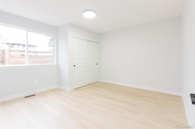 unfurnished bedroom with light wood-type flooring, visible vents, and baseboards