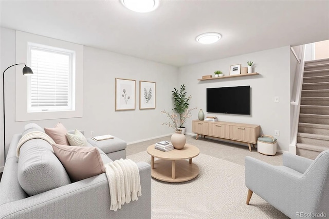 living area featuring light carpet, stairs, and baseboards