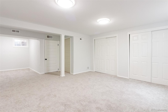 unfurnished bedroom featuring carpet flooring, visible vents, and multiple closets