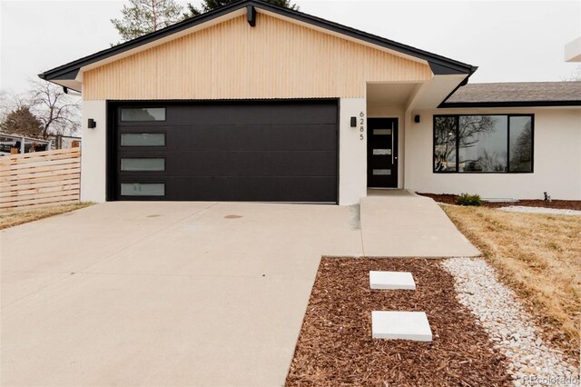 view of front facade with concrete driveway, fence, and an attached garage