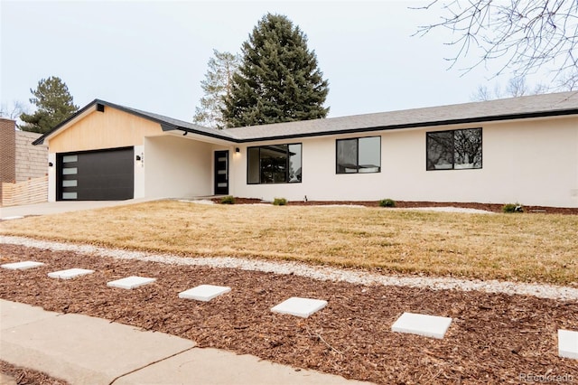 view of front of home featuring a garage, driveway, a front lawn, and stucco siding